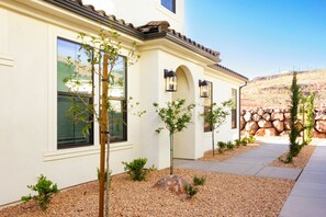 A building with a white exterior, a tiled roof, and a stone wall in the background. - Southern Utah Wonder... Under the Sage Arches. Your family will be close to everything from parks to town when you stay at this centrally-located house. (Washington)