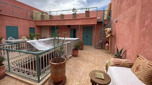 A courtyard with a covered seating area, potted plants, a staircase, and a bed with pillows. - Luxurious 5-bedroom Apartment in Marrakesh With Full Accessibility (Marrakech)