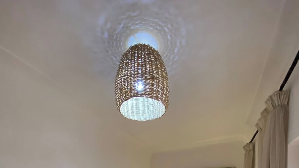 A neatly made bed with white linens and towels, a decorative mirror above it, and a woven ceiling light fixture. - Luxurious 5-bedroom Apartment in Marrakesh With Full Accessibility (Marrakech)