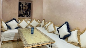 A room with a sofa, a table, and a wall-mounted light fixture. - Luxurious 5-bedroom Apartment in Marrakesh With Full Accessibility (Marrakech)