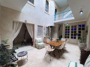A spacious patio with a wooden table and wicker chairs, a staircase, and a view of a pool. - Luxurious 5-bedroom Apartment in Marrakesh With Full Accessibility (Marrakech)