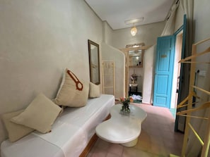 A room with a sofa, a coffee table, a mirror, a blue door, and a hanging light fixture. - Luxurious 5-bedroom Apartment in Marrakesh With Full Accessibility (Marrakech)