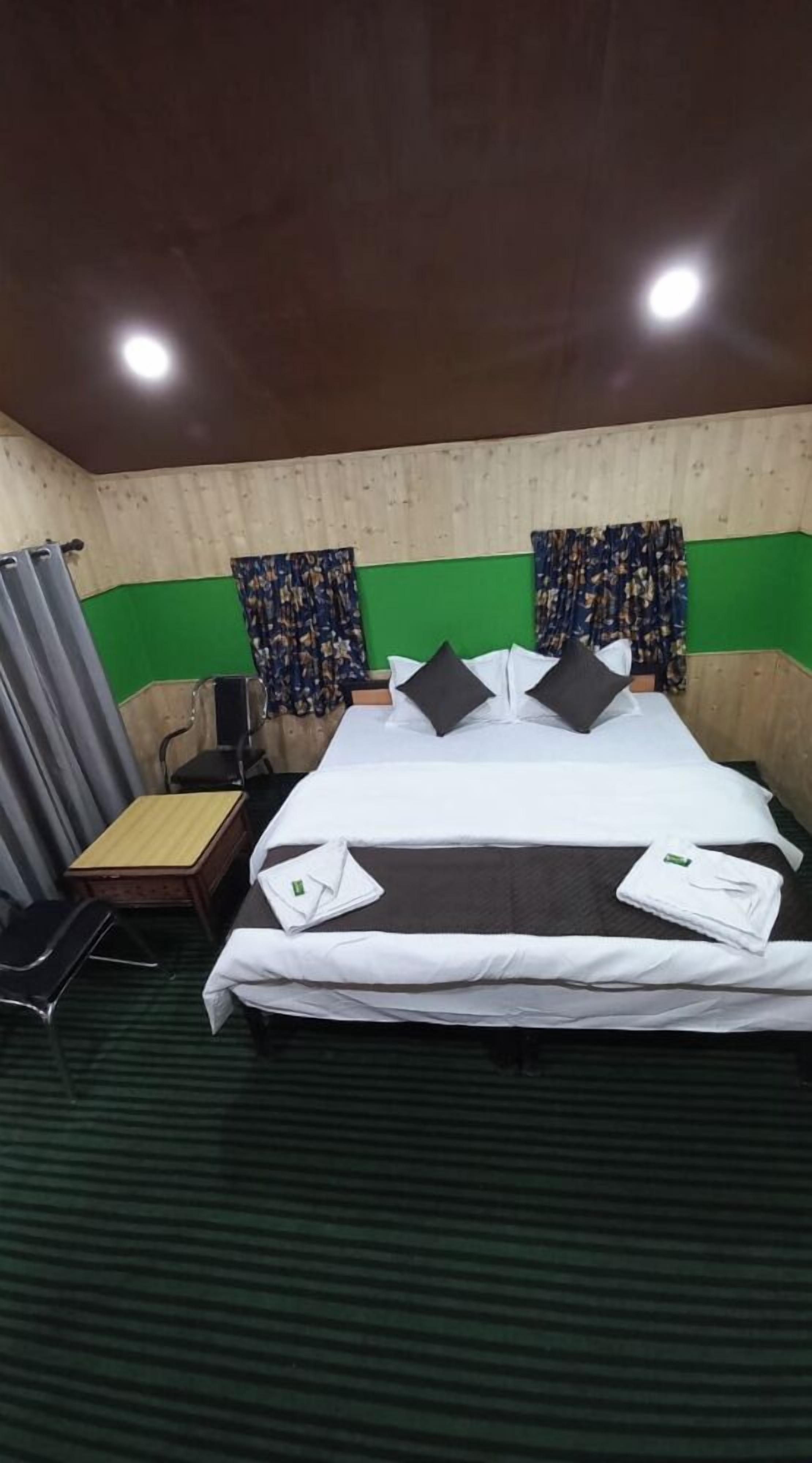 A room with a bed, a chair, a desk, and a green wall.