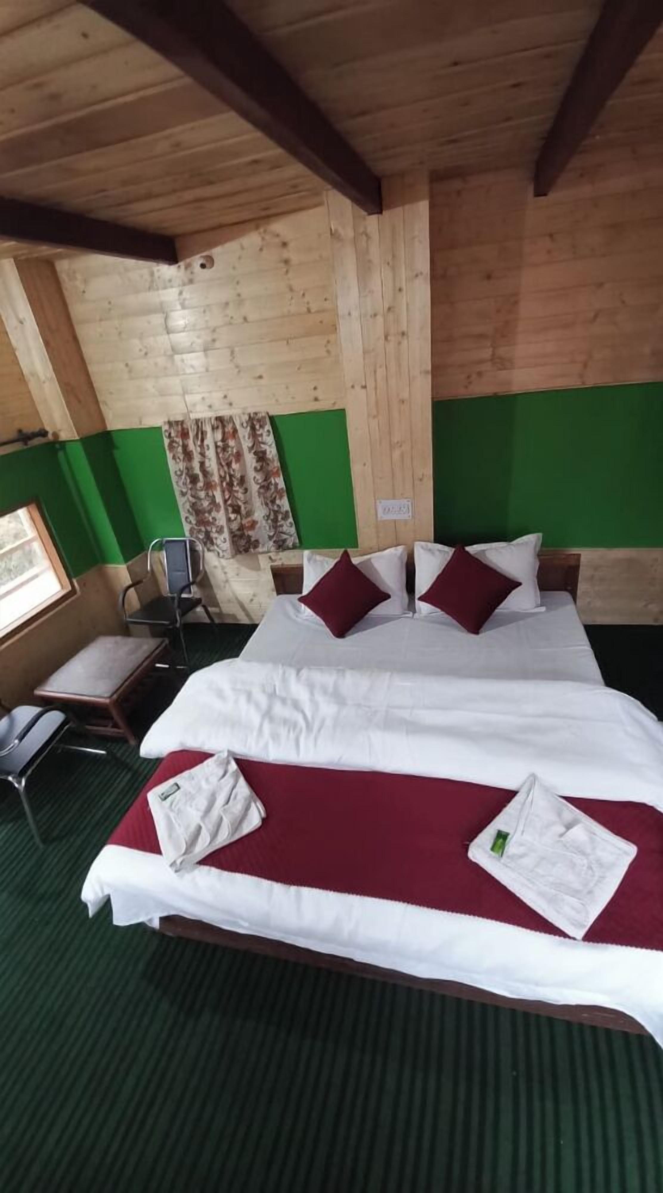 A wooden cabin room with a bed, green walls, and a window.