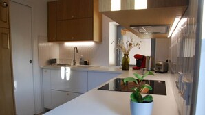 Une cuisine moderne avec des meubles blancs, un îlot central et une plante en pot.