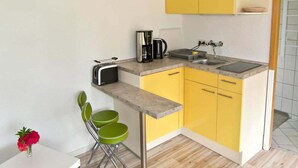 A compact kitchen with yellow cabinets, a built-in sink, a toaster, and a coffee maker. - Ferienhaus mit Kamin am Achterwasser in Lutow (Luetow)