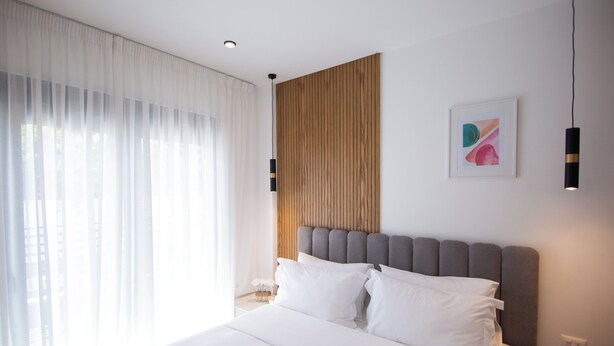 Una habitación de hotel moderna con una cama grande, un panel decorativo de madera y una obra de arte abstracta enmarcada.
