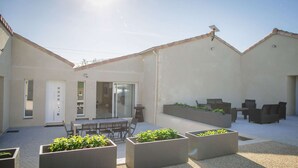 A courtyard with a dining area, outdoor seating, and planters.