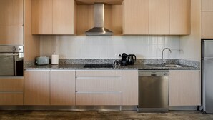 A modern kitchen with wooden cabinets, a stainless steel range hood, a granite countertop, a dishwasher, and a sink. - Casa Canto: Villa with Private Heated Pool, Wi-Fi, and Air Conditioning (Estela)