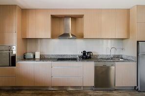 A modern kitchen with wooden cabinets, a stainless steel range hood, a granite countertop, a dishwasher, and a sink. - Casa Canto: Villa with Private Heated Pool, Wi-Fi, and Air Conditioning (Estela)
