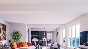 A modern living room with a sofa, a dining table, and a TV.