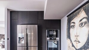 A modern kitchen with a stainless steel refrigerator, built-in oven, and a water dispenser.