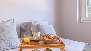A bed with pillows, a tray with breakfast items, and a window.