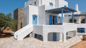 A white building with blue accents, stone steps, and a clear sky. - Seaside Paros Ambelas Villa 1 (Paros)