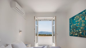 A hotel room with a bed, a painting, and a view of the sea. - Seaside Paros Ambelas Villa 1 (Paros)