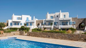 A modern white building with blue shutters, a stone wall, and a swimming pool. - Seaside Paros Ambelas Villa 1 (Paros)