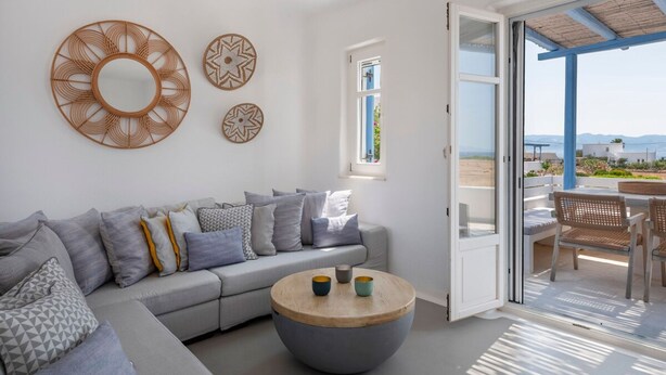 A modern living room with a grey sofa, a round coffee table, and decorative wall art. - Seaside Paros Ambelas Villa 1 (Paros)