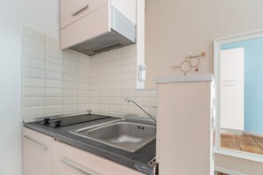 Eine Küche mit weißen Fliesen, einer Edelstahl-Spüle und einem Gasherd.