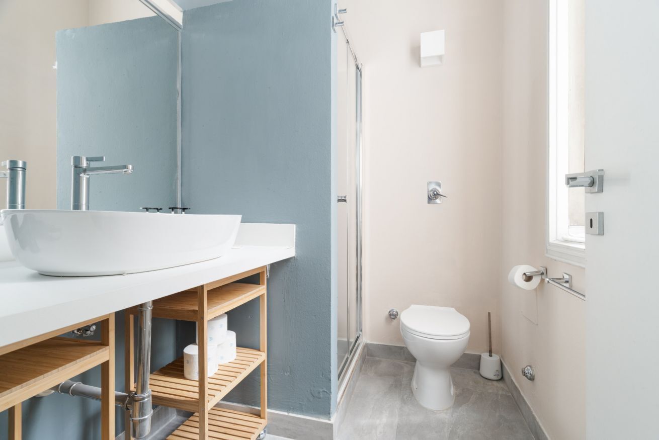 Une salle de bain moderne avec un lavabo blanc, un miroir et des toilettes.