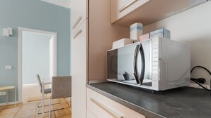 Una cocina moderna con microondas integrado, un comedor con una silla y suelo de madera.