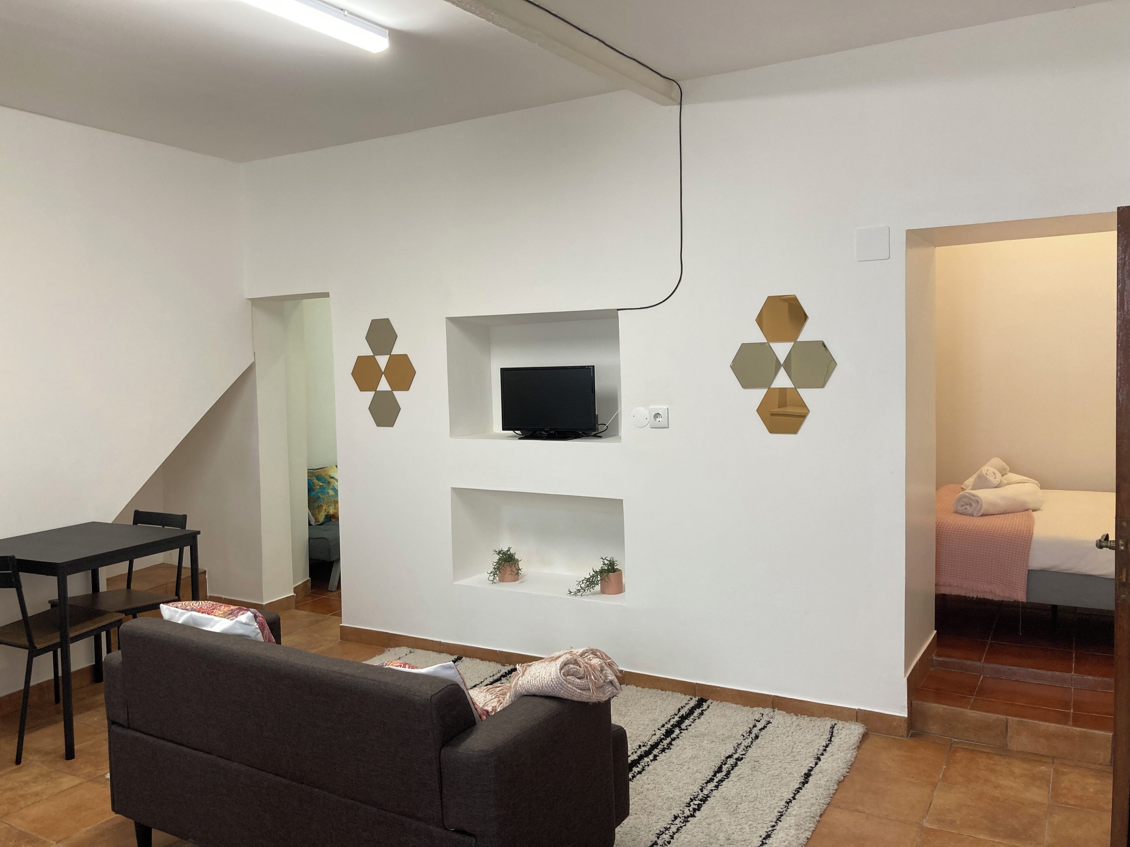 Un salon moderne avec un canapé, un téléviseur fixé au mur et un coin repas comprenant une table et des chaises.