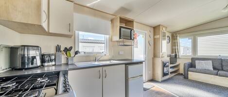 A compact kitchen with a gas stove, toaster, microwave, and sink.