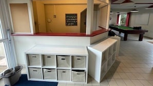Une table de billard, une poubelle et un meuble de rangement doté de plusieurs compartiments.