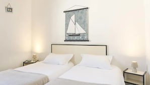 Une chambre d’hôtel avec deux lits, une œuvre d’art représentant un voilier accrochée au mur et des lampes de chevet.