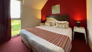 Une chambre avec un grand lit, deux tables de chevet, une fenêtre avec des rideaux et un mur d  ’accent de couleur rouge.