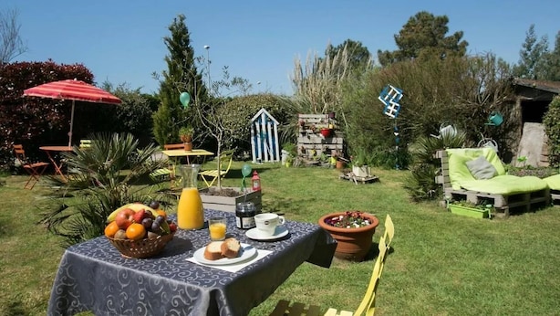 Un jardin aménagé avec une table dressée pour le petit-déjeuner, une chaise et un fauteuil.
