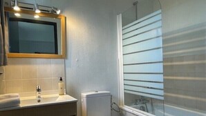 Une salle de bain équipée de toilettes, d’un lavabo, d’un miroir et d’une douche.