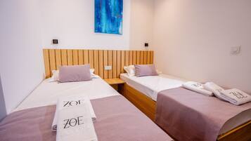 A hotel room with two beds, wooden headboards, and towels with the hotel name.