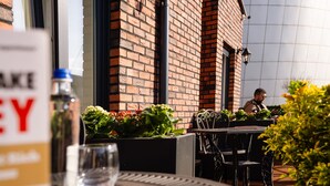Een terras met bakstenen muren, metalen stoelen en een tafel.
