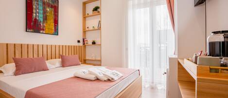 Una habitación de hotel moderna con una cama de madera, un televisor de pantalla plana, una cafetera y un ventanal con cortinas.