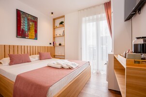 Una habitación de hotel moderna con una cama de madera, un televisor de pantalla plana, una cafetera y un ventanal con cortinas.