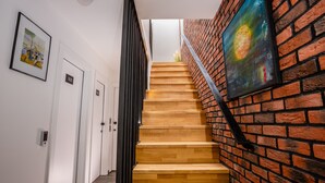 Een trap met houten treden en een bakstenen muur, leidend naar een kamer met een deur waarop '103' staat.