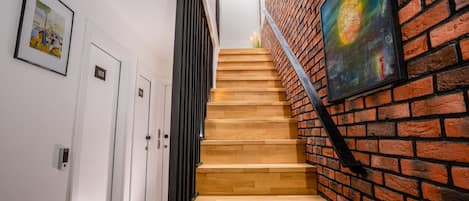 A staircase with wooden steps and a brick wall, leading to a room with a door labeled '103'.