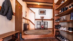 Un intérieur en bois avec un escalier, un tapis rond, une étagère à chaussures et un porte-manteau.