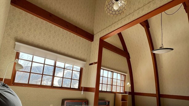 Une chambre à coucher avec un grand lit, un bureau, une chaise, une lampe et une fenêtre donnant sur un beau paysage.