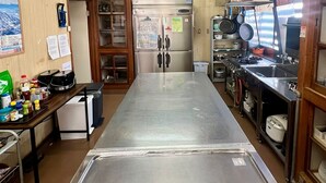 Une cuisine dotée d’un plan de travail en acier inoxydable, de meubles de rangement en bois, d’un réfrigérateur et d’un évier.