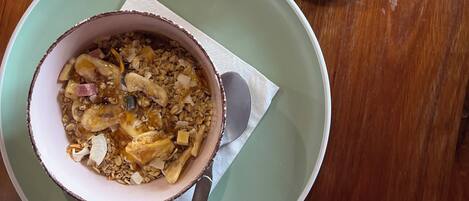 A meal with a bowl of granola and fruit, a cup of coffee, and a wallet on a wooden table.