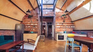 Una cucina compatta con una parete in mattoni, un'area pranzo con un tavolo e sedie in legno, e un piccolo angolo salotto con un divano.
