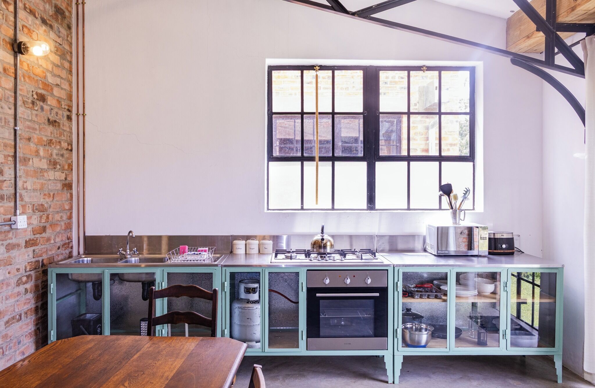 A kitchen with a gas stove, oven, and a window with a view of buildings.