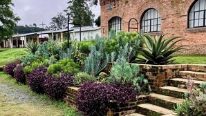 Un edificio in mattoni con finestre ad arco e un giardino con diverse piante.