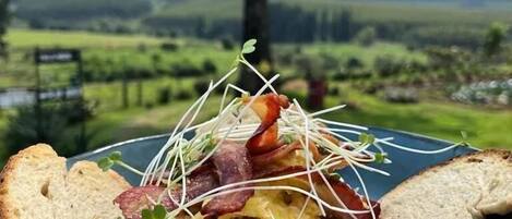 Eine Schüssel Essen mit Brot auf einem Tisch, vor einer grünen Landschaft.