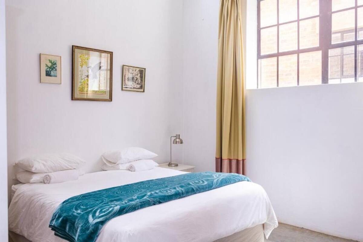 A bedroom with a bed, a nightstand, a lamp, and three framed pictures on the wall.