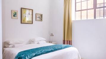 A bedroom with a bed, a nightstand, a lamp, and three framed pictures on the wall.