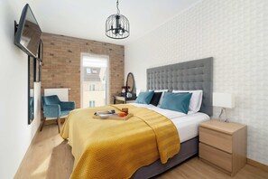Ein modernes Schlafzimmer mit Bett, Nachttisch, Fernseher an der Wand.