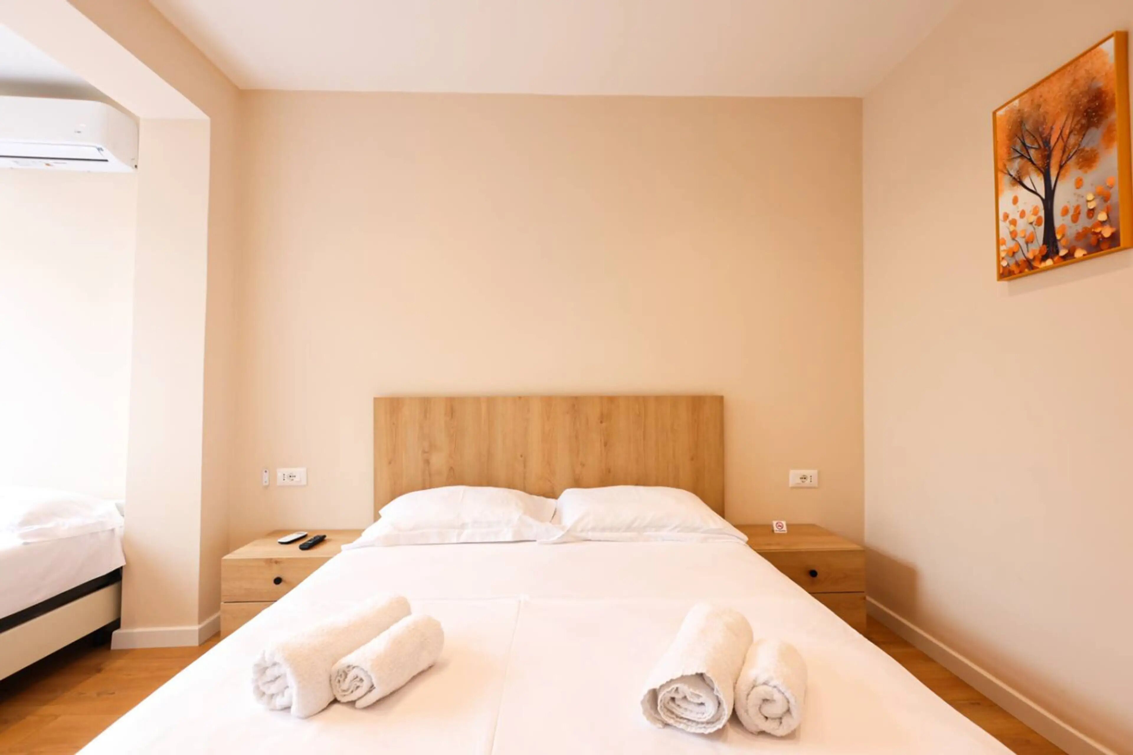 Una habitación de hotel con una cama, dos mesitas de noche, un cuadro en la pared y una ventana.