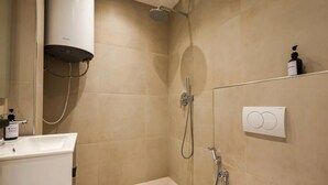 Un baño con ducha, lavamanos y dispensador de jabón.